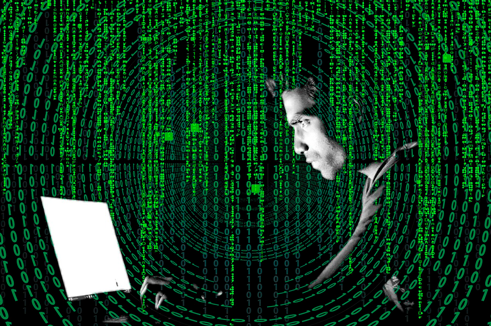 codici 0 1 e in primo piano ragazzo di profilo al pc