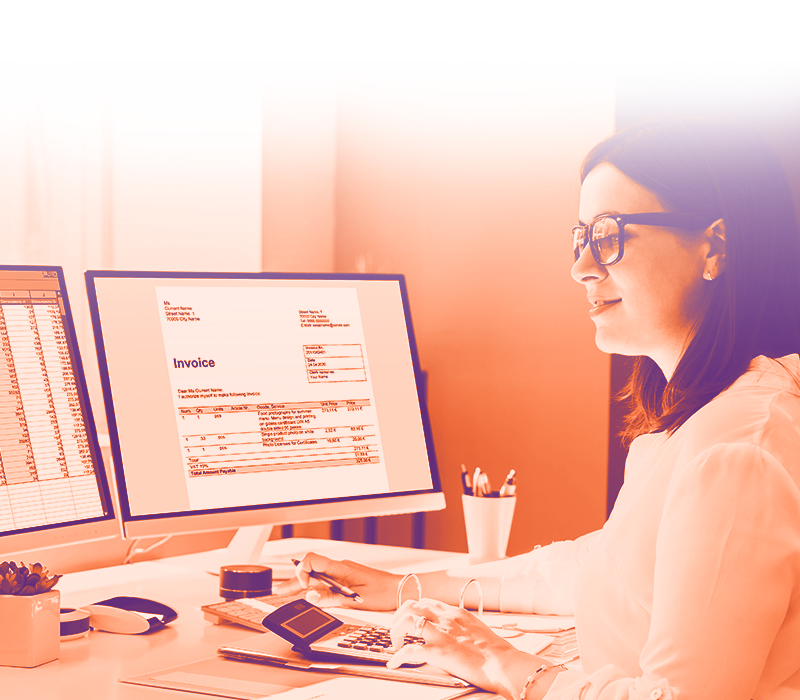 foto con gradiente arancione dove appare una ragazza di profilo sulla destra che lavoro con due pc davanti e sullo schermo di vede una fattura e un foglio excel di lavoro