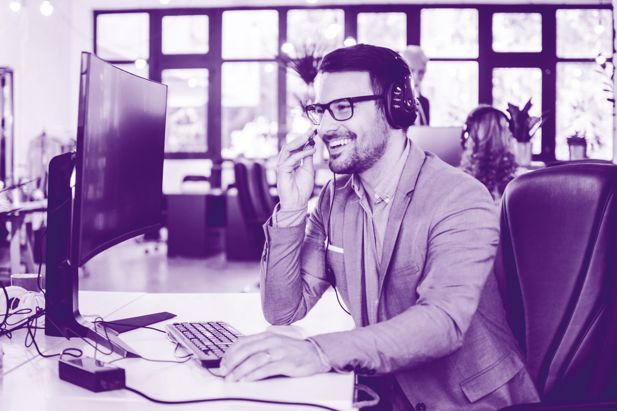 foto con gradiente viola con uomo al pc che parla al telefono con le cuffie