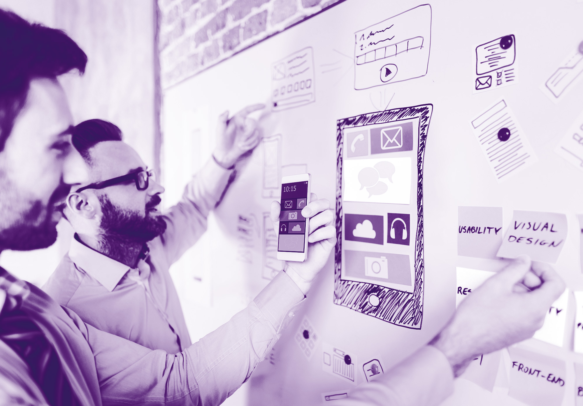 foto con gradiente viola chiaro dove troviamo degli uomini che scrivono su una lavagna a muro creando un mockup di sviluppo e degli appunti su post it