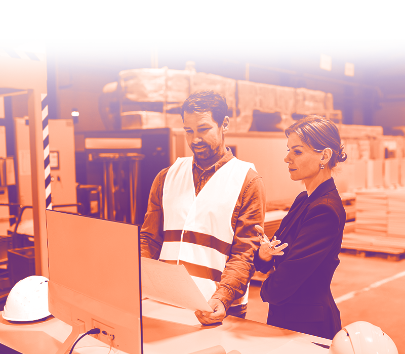 immagine con gradiente arancione sfumato sul bianco con una signora in vestito e un uomo vestito da lavoro che guardano un foglio che tengono in mano. sono entambi all'interno di un magazzino